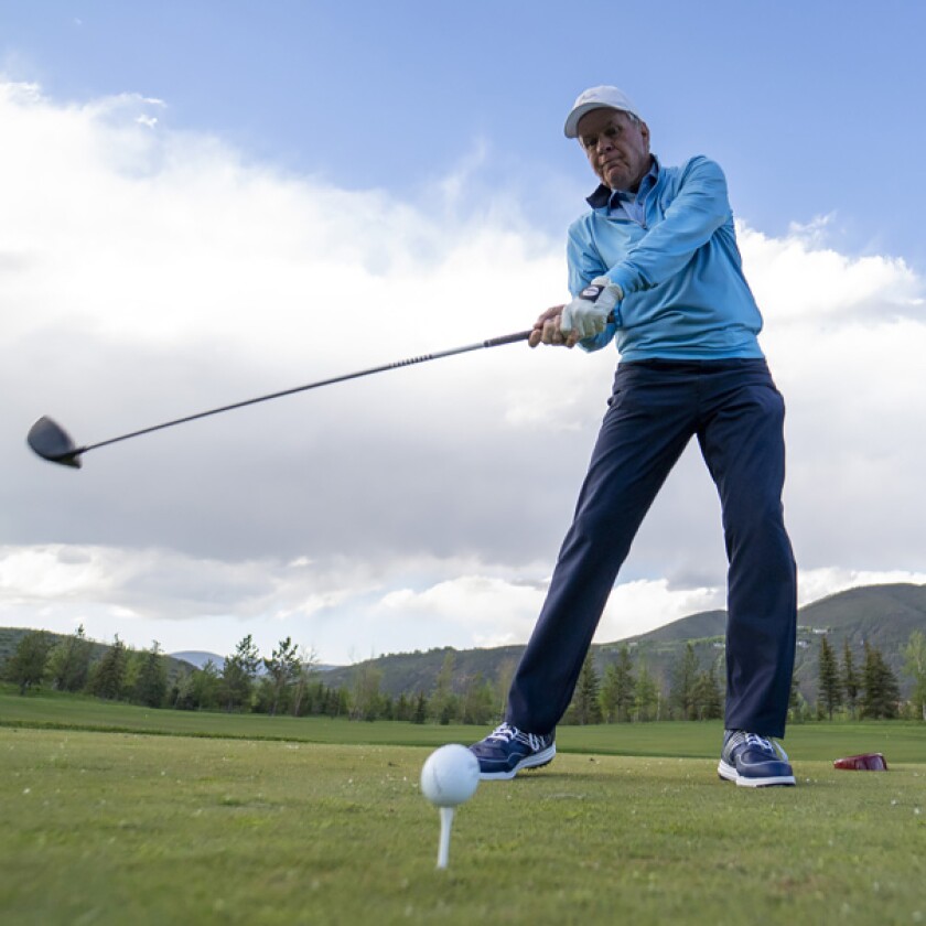 Golfer swinging with lower back tightness
